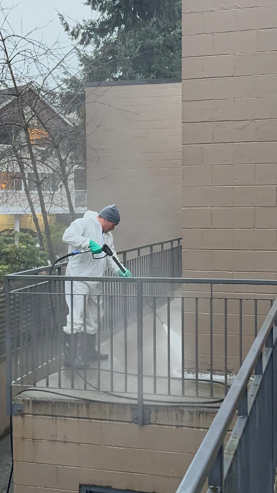 Travailleur effectuant un lavage à pression d'une entrée sur la Rive-Nord
